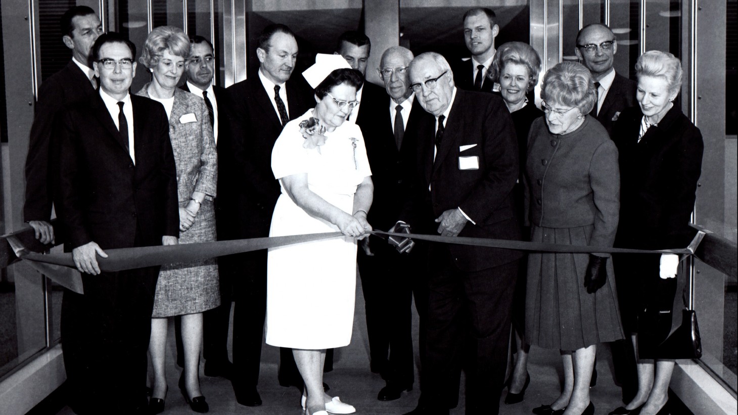 A nurse and group of dignitaries at a ribbon cutting 