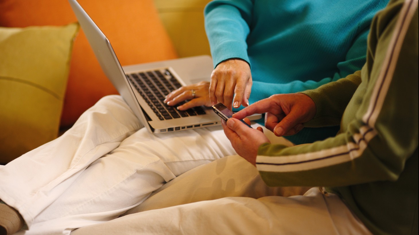 hands at a laptop and a smartphone 