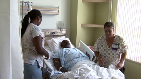 Two care providers help get a patient out of bed 