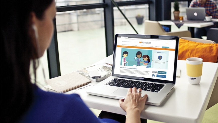 Woman sitting in a cafe, looking at the LMP website on her laptop.