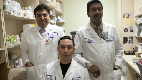 Three male pharmacy workers posing in their white lab coats 