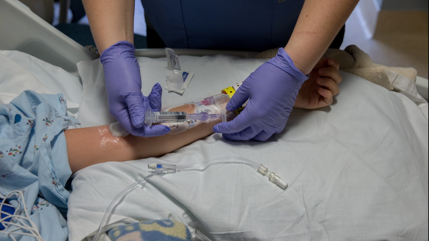 A pair of hands inserting an IV in a patient's arm 