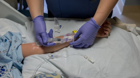 A pair of hands inserting an IV in a patient's arm
