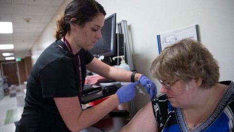 Nurse giving a female patient a flu shot 