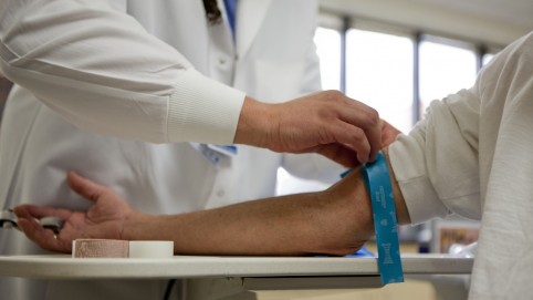 A provider preparing a patient's arm for a blood draw 