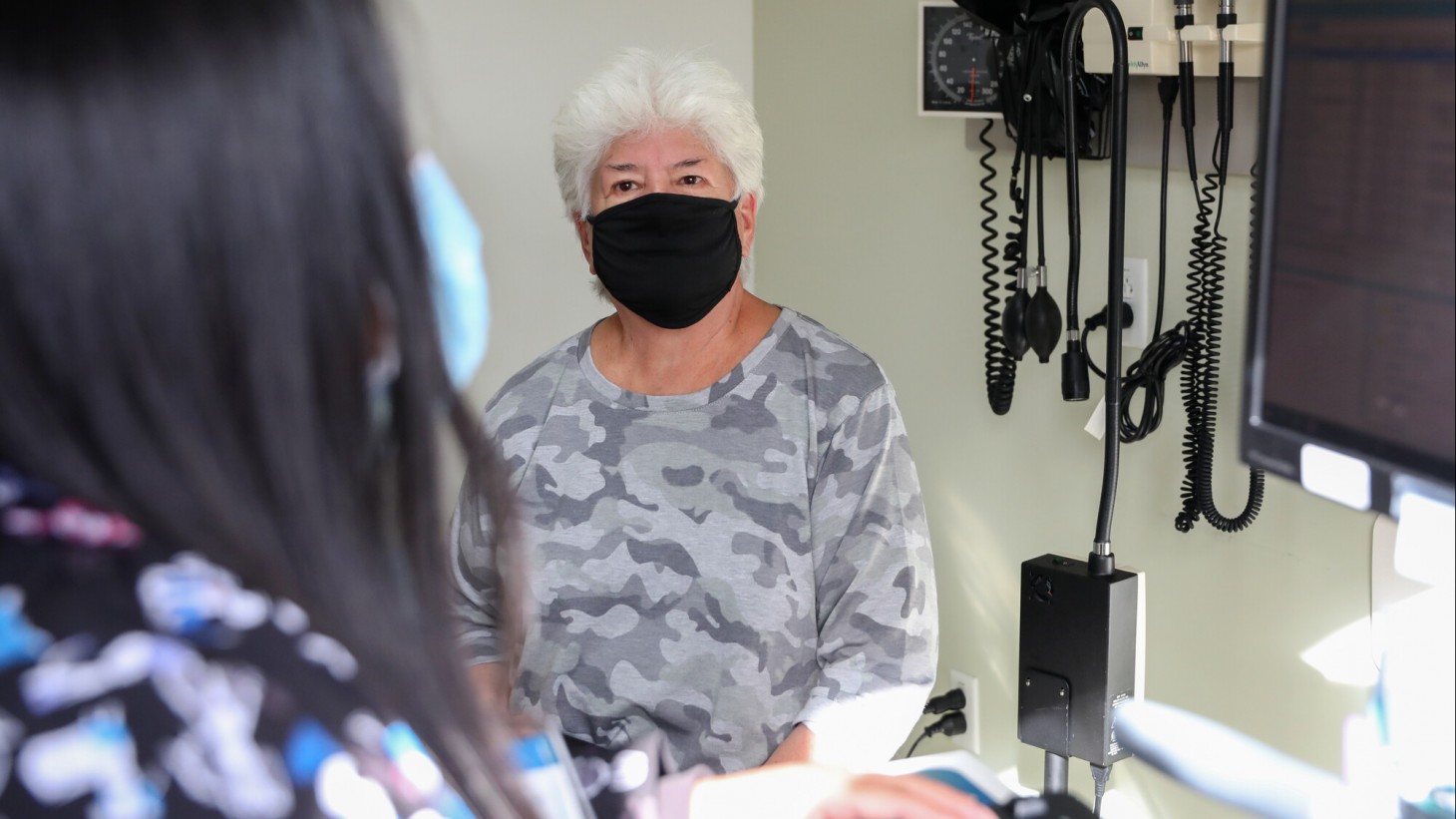 Elderly female patient in a doctor's office, wearing a mask