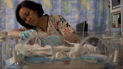 Nurse tends to an infant in an incubator