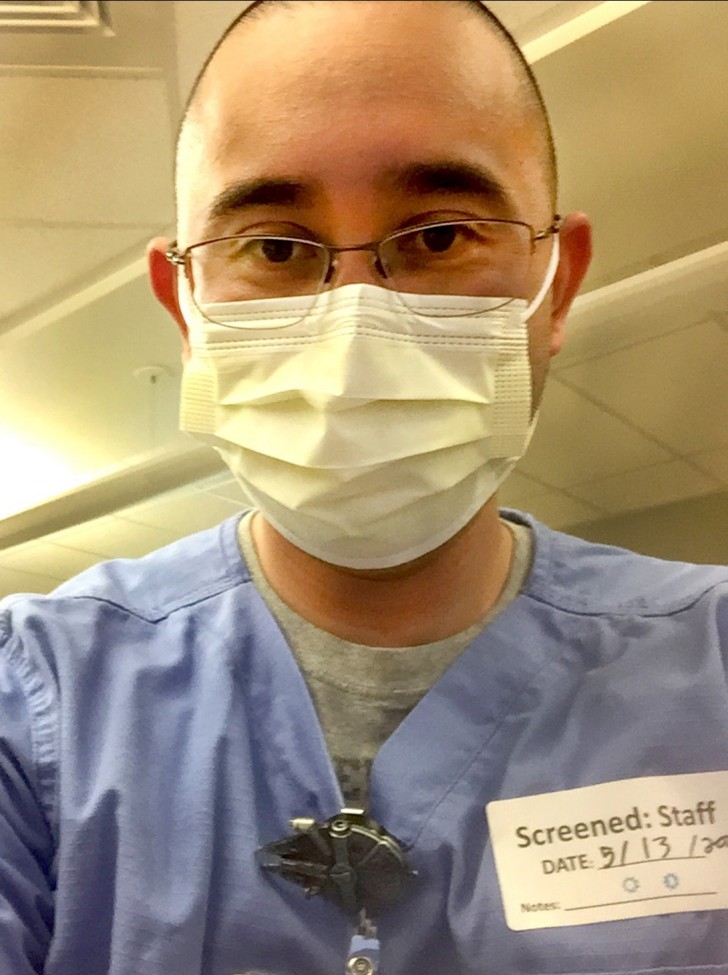 Portrait of a male health care worker in blue scrubs, wearing a mask